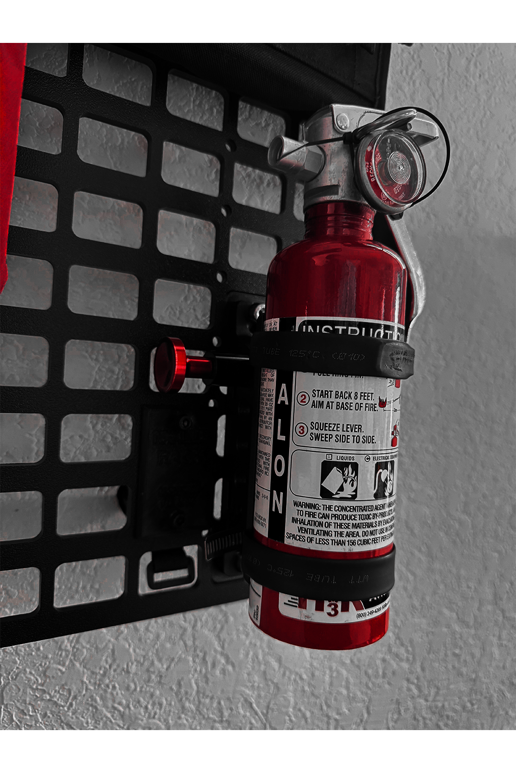Red fire extinguisher mounted on a molle rack with a textured background