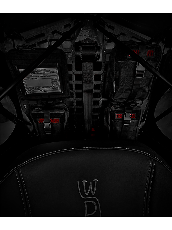 Dark interior of an aircraft with tactical bags and equipment attached to a Molle Rack.