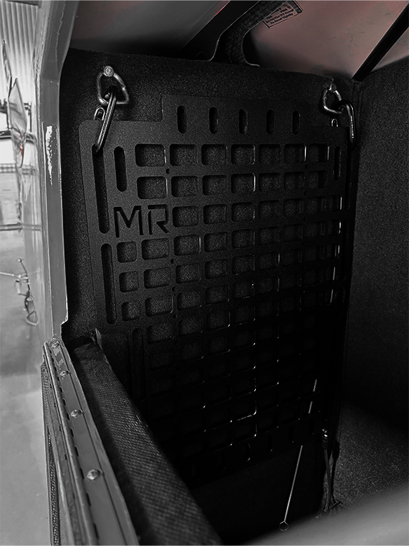 Dark interior of an aircraft with a Molle Rack attached.