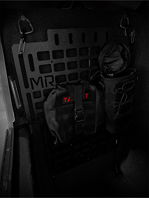 Dark interior of an aircraft with tactical bags and equipment attached to a Molle Rack.