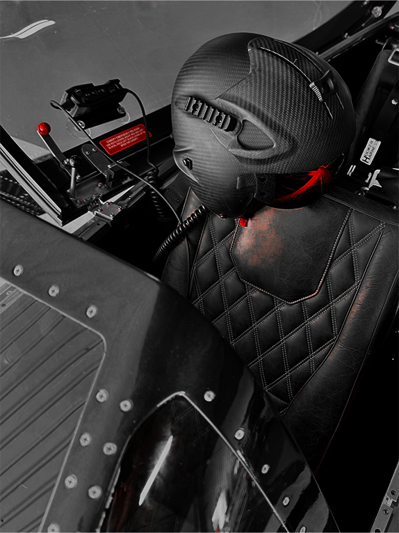 Close-up of a black leather seat with quilted pattern and red stitching on a vehicle.